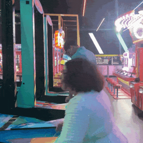a man and a woman are playing a game in an arcade with a sign that says n on it