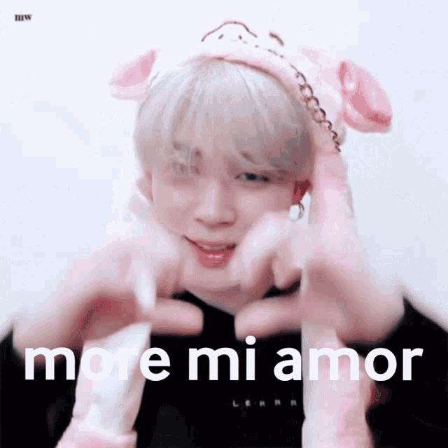 a person wearing a pink hat making a heart with their hands