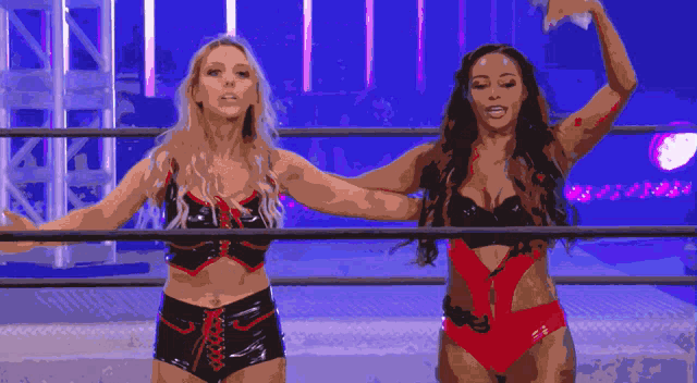 two women in bikinis are standing in a ring with their arms outstretched