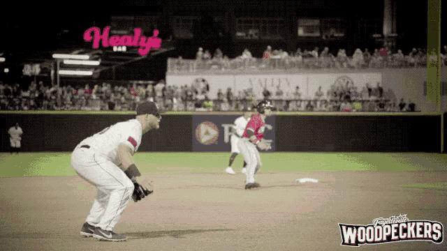 a baseball game is being played in front of a sign that says healy 's bar on it