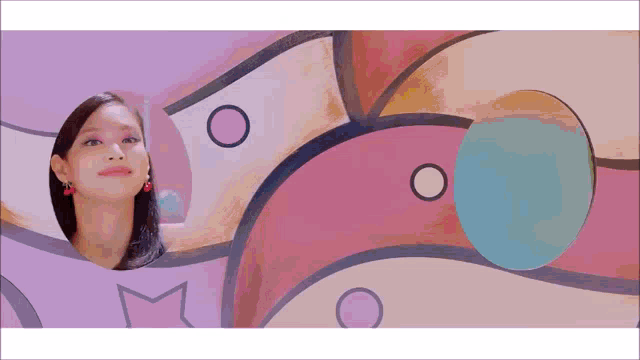 a woman is standing in front of a colorful wall with circles and dots .