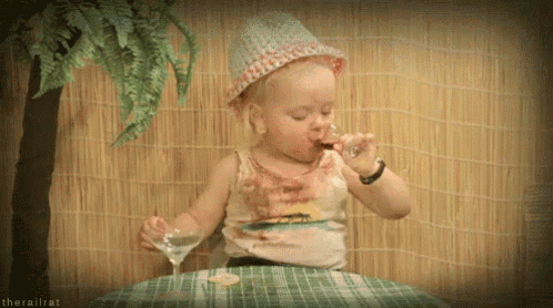 a little girl wearing a hat is drinking from a glass