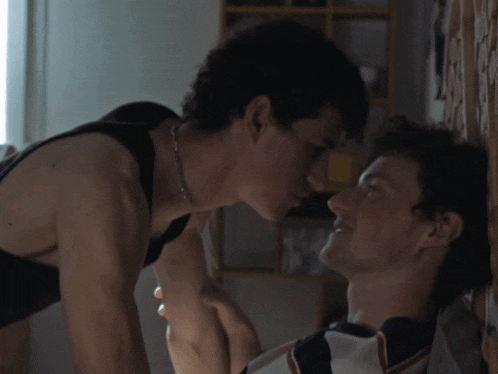 two young men are kissing each other in a dark room
