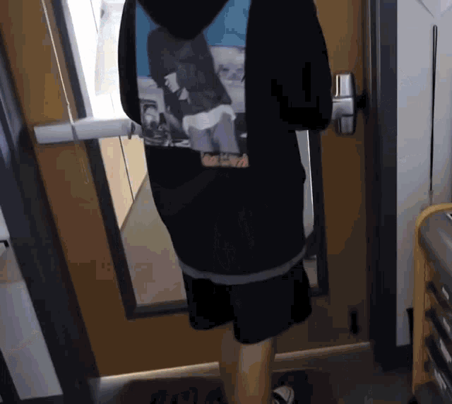 a person standing in front of a door wearing a black hoodie
