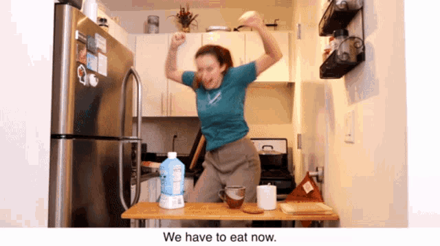 a woman is dancing in a kitchen with the words we have to eat now