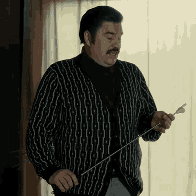 a man in a black and white striped sweater is holding a cane