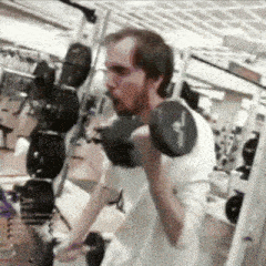 a man is lifting a dumbbell in a gym with a white shirt on