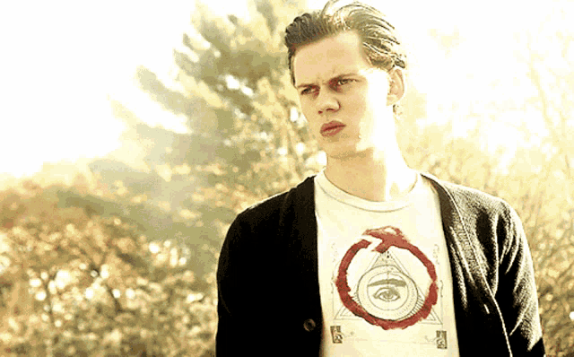 a man wearing a black cardigan and a white shirt with a red circle on it