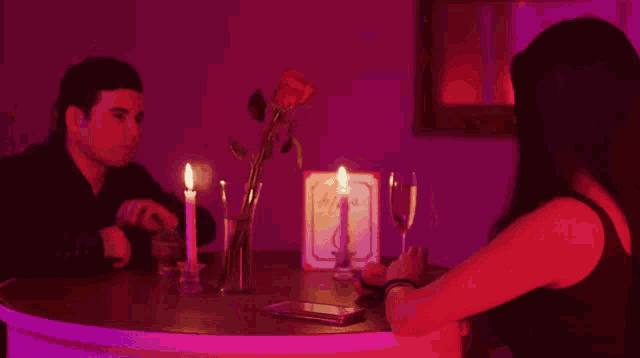 a man and a woman are sitting at a table with candles and a menu that says ' dinner ' on it