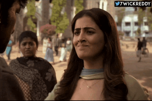 a woman with a sad look on her face is standing in front of a sign that says ' 7wickreddy ' on it