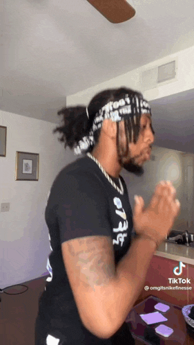 a man wearing a headband and a black shirt is dancing in a room .