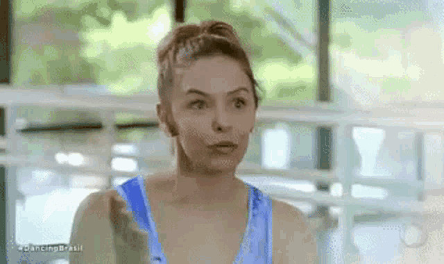 a woman in a blue tank top is making a face .