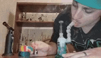 a woman in a blue hat is smoking a bong