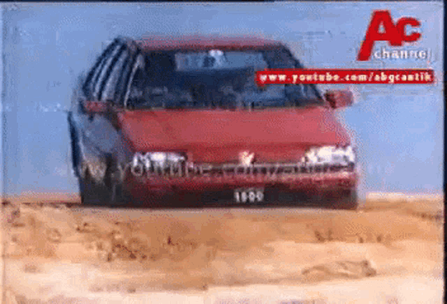 a red car from the year 1990 is driving through the desert