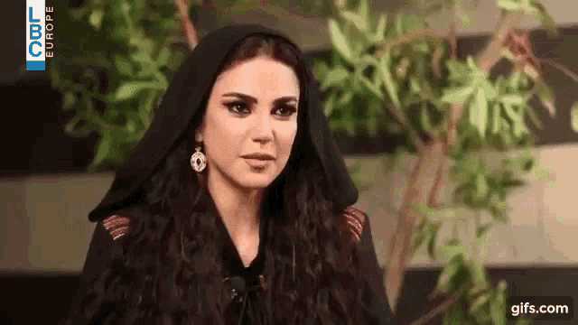 the woman is wearing a black hooded jacket and earrings .