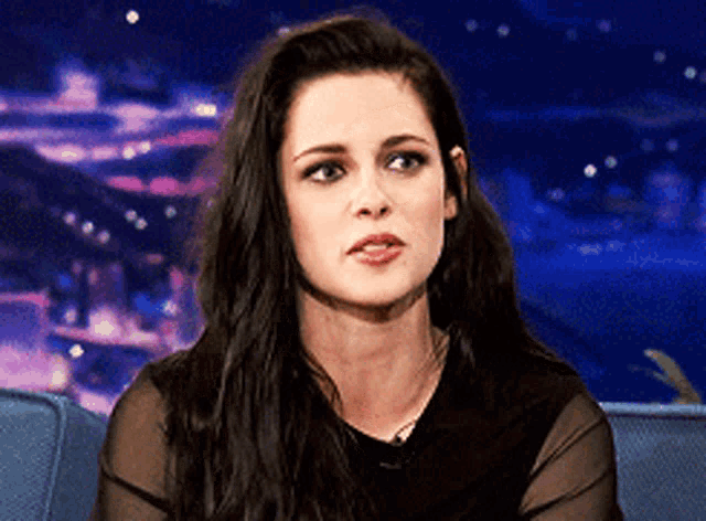 a woman with long hair is sitting on a couch and looking at the camera