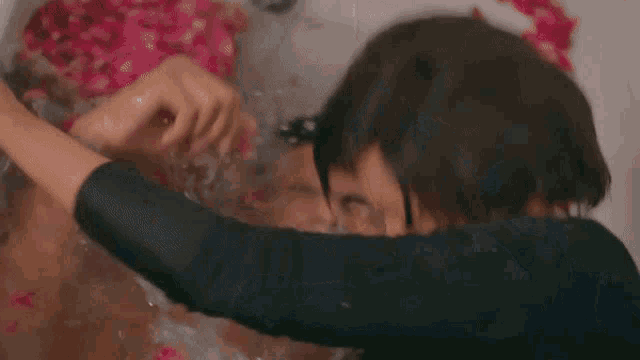 a man is laying in a bathtub with water pouring out of his mouth .