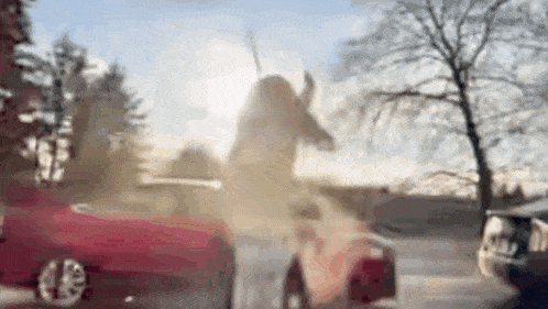 a woman is standing in front of a red car .