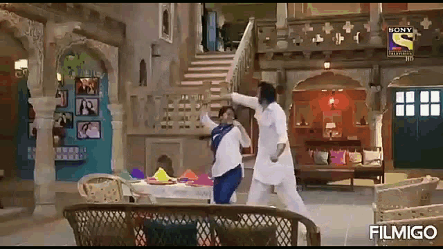 a man and a woman are dancing in a living room with stairs in the background .