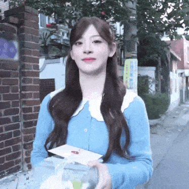 a woman in a blue sweater holds a gift box