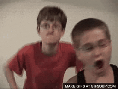 two young boys are standing next to each other with their mouths open and making funny faces .