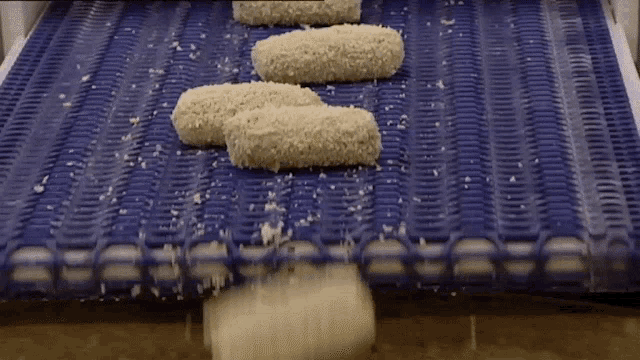 a conveyor belt with a few pieces of food going down it