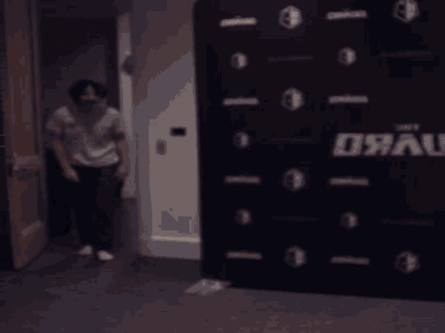 a man in a white shirt is dancing in front of a wall that says ' jrau ' on it