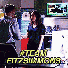 a man and a woman are standing next to each other in an office with the words #team fitzsimmons
