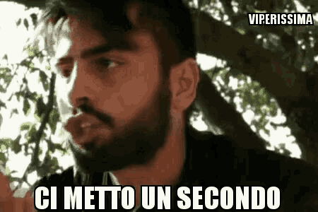 a man with a beard says ci metto un secondo in front of a tree