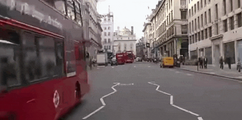 a red double decker bus is driving down a busy street