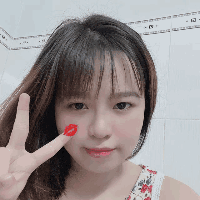 a girl with a red lip on her face giving a peace sign