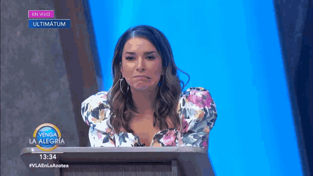 a woman sitting at a podium with a sign that says en vivo ultimatum