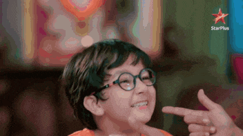 a young boy wearing glasses is pointing at his face with a star plus logo behind him