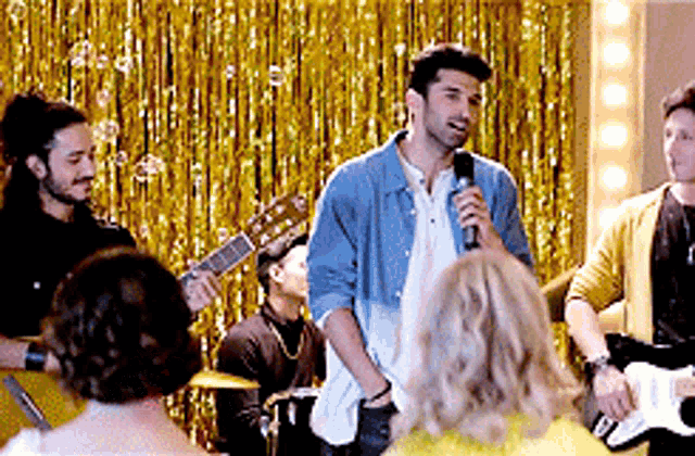 a man is singing into a microphone in front of a band