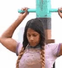 a woman is standing next to a pole holding a green stick over her head .