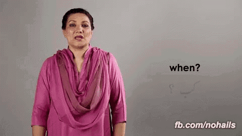 a woman in a pink dress is standing in front of a gray wall and asking when .