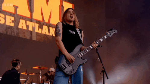 a man is playing a guitar in front of a sign that says bbc