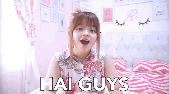 a girl is sitting on a bed with her mouth open and the words hai guys written on her chest .