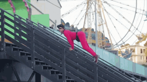 a man in a pink outfit is crawling up a set of stairs