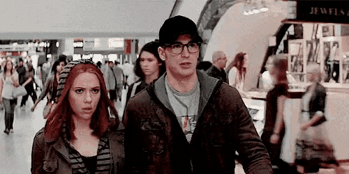 a man and a woman are standing next to each other in a crowded mall .