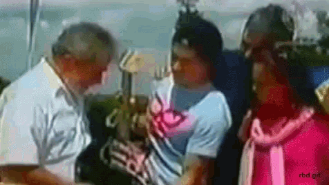 a man in a white shirt is talking to a woman in a pink scarf .
