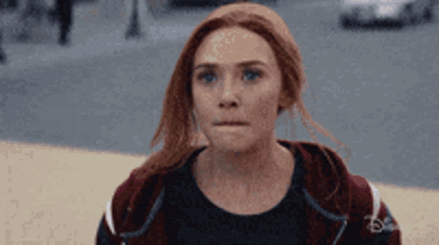 a close up of a woman 's face with red hair and blue eyes .