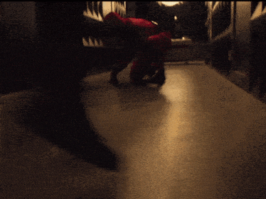 a person in a red suit is crawling on the floor in a dark hallway