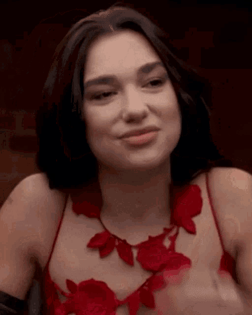 a close up of a woman wearing a red dress and a necklace with roses on it .