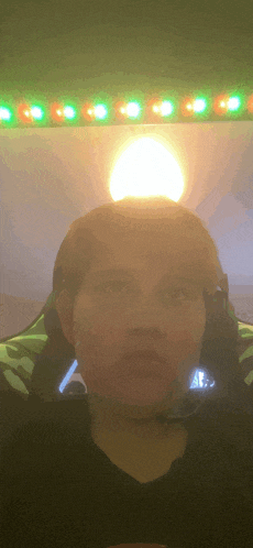 a man wearing a headset is looking at the camera with a light behind him