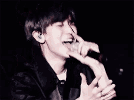 a man is singing into a microphone in a dark room while making a funny face .