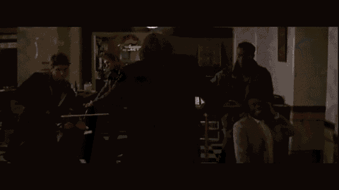 the joker from the movie the dark knight is holding a bat in his mouth .