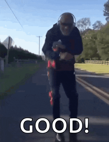 a man wearing headphones and sunglasses is walking down a road with the words good written on the bottom