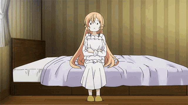 a girl with long blonde hair is sitting on a bed with her arms crossed
