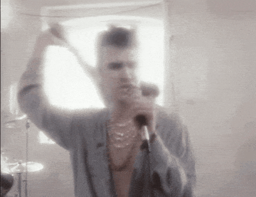 a man singing into a microphone while holding a stick